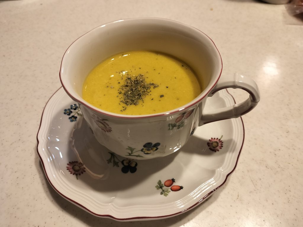 花柄のカップに盛り付けた庭のかぼちゃで作った黄色いスープ