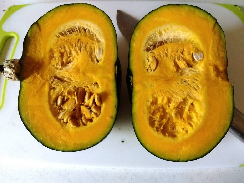 半分に切ったかぼちゃの黄色い果肉と種